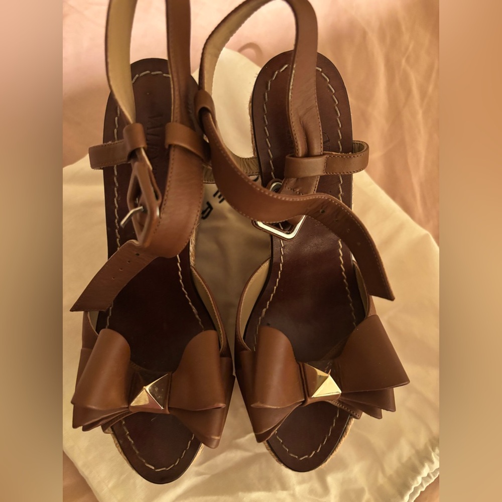 Valentino Garavani Brown Bow T-Strap Sandals with Gold Pyramid Accent.